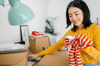 Female young small business owner selling clothes online while working at home.