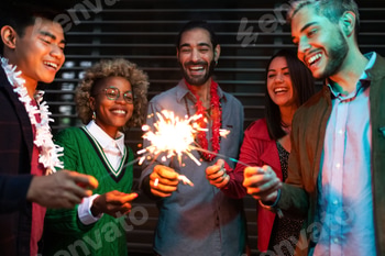 Smiling young multiracial friends having night party with sparklers.