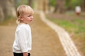 Cute blonde kid in a white sweater is walking around a park. I - PhotoDune Item for Sale