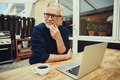 Senior man sitting outside drinking coffee and using a laptop - PhotoDune Item for Sale