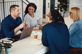Smiling coworkers talking together at a table in an office - PhotoDune Item for Sale