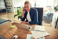 Smiling businessman sitting in his office talking on a cellphone - PhotoDune Item for Sale