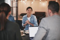 Smiling Asian businesswoman talking to coworkers during a meeting - PhotoDune Item for Sale