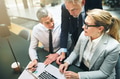 Mature manager discussing business with two colleagues on a laptop - PhotoDune Item for Sale