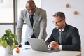 Two smiling businessmen talking together and working with a laptop - PhotoDune Item for Sale