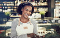 Smiling young African cafe owner working with a digital tablet - PhotoDune Item for Sale