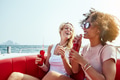 Two laughing young friends relaxing on a boat with drinks - PhotoDune Item for Sale