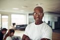 Confident African businessman smiling with colleagues in the background - PhotoDune Item for Sale