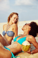 Two smiling female friends suntanning together on a tropical beach - PhotoDune Item for Sale