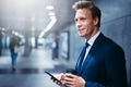 Smiling businessman waiting for a subway train reading text messages - PhotoDune Item for Sale