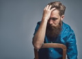 Depressed man with hand on forehead over gray - PhotoDune Item for Sale