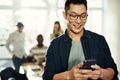 Smiling young Asian designer reading text messages in an office - PhotoDune Item for Sale