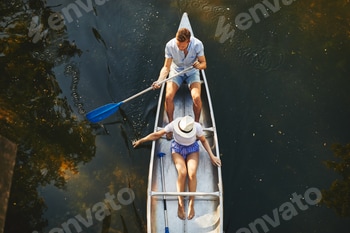 Young couple paddling their canoe on a lake in summer