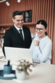 Two smiling businesspeople using a laptop together in an office - PhotoDune Item for Sale