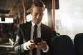 Smiling young businessman standing on a bus reading text messages - PhotoDune Item for Sale