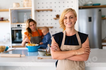 Smiling young woman chef cook in apron standing at the kitchen
