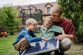 Father and his sons holding solar panel in the garden, learning about photovoltaics and green energy - PhotoDune Item for Sale