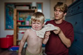 Father putting shirt on little son, changing from pajamas in the morning. Boy is sad, crying. - PhotoDune Item for Sale