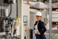 Female manager standing in modern industrial factory. Manufacturing facility with robotics and - PhotoDune Item for Sale