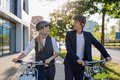 Colleagues commuting through the city, talking and walking by bike on street. Middle-aged city - PhotoDune Item for Sale