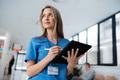 Portrait of confident female doctor standing in Hospital corridor. Beautiful nurse wearing blue - PhotoDune Item for Sale