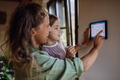 Girl helping mother to adjust, lower heating temperature on thermostat. Concept of sustainable - PhotoDune Item for Sale