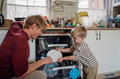 Little boy helping father to load dishwasher after breakfast. Cleaning the kitchen before leaving to - PhotoDune Item for Sale