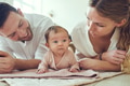 Smiling young parents lying with their baby girl at home - PhotoDune Item for Sale