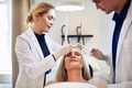 Woman lying on clinic table with doctors discussing surgery options - PhotoDune Item for Sale