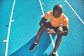 Young athlete sitting on a track checking his fitness watch - PhotoDune Item for Sale