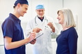 Doctor talking to woman while smiling assistant writing in tablet - PhotoDune Item for Sale