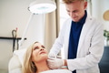Smiling doctor performing injections on a mature client's face - PhotoDune Item for Sale