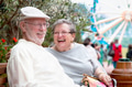 Laughing Senior Adult Couple Enjoying The Carnival From the Outdoor Bench. - PhotoDune Item for Sale
