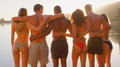 Rear View Of Group Of Young Friends In Swimwear With Arms Around Each Other By Lake With Lens Flare - PhotoDune Item for Sale