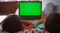 Rear View Shot Of Two Children Sitting On Sofa At Home Using Green Screen Laptop Computer Together - PhotoDune Item for Sale