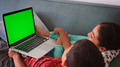 Rear View Shot Of Two Children Sitting On Sofa At Home Using Green Screen Laptop Computer Together - PhotoDune Item for Sale