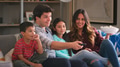 Family Sitting On Sofa Watching TV And Eating Popcorn Together - PhotoDune Item for Sale