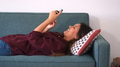 Woman Lying On Sofa At Home Browsing Online Or checking Social Media And Messages On Mobile Phone - PhotoDune Item for Sale