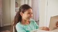Smiling Young Girl Sitting At Desk In Bedroom At Home Using Digital Tablet - PhotoDune Item for Sale