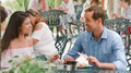 Mid Adult Couple Sitting At Table Enjoying Meal At Outdoor Cafe Or Restaurant - PhotoDune Item for Sale