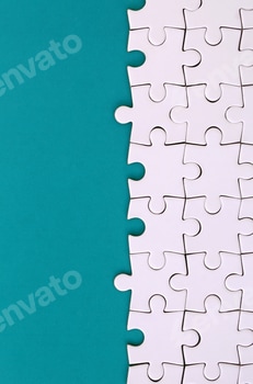 Fragment of a folded white jigsaw puzzle on the background of a blue plastic surface. Texture