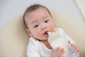 Little baby drinking milk with caregiver hand - PhotoDune Item for Sale