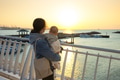 Mother holding baby watching sunset over ocean - PhotoDune Item for Sale
