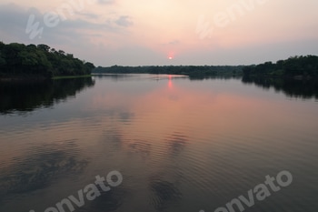 Sunset over tranquil river surrounded by lush greenery in Amazon region