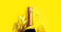 Champagne bottle with christmas gold ribbon on pastel yellow background. New year celebration banner - PhotoDune Item for Sale