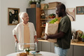 Senior Caucasian Woman Smiling While Receiving Groceries from Black Man - PhotoDune Item for Sale