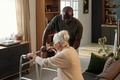 Black Man Encouraging Senior Caucasian Woman Walking with Walker - PhotoDune Item for Sale