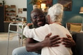 Young Black Man Hugging Senior Caucasian Woman in Living Room - PhotoDune Item for Sale