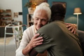 Senior Caucasian Woman Embracing Young Black Man Indoors Smiling - PhotoDune Item for Sale