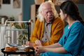 Senior Caucasian Man Talking with Young Adult Latin Woman in Healthcare Setting - PhotoDune Item for Sale